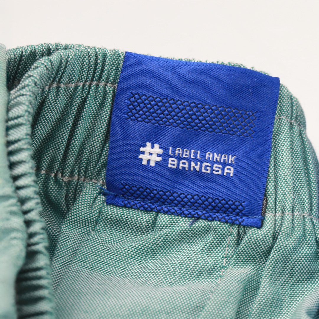 Label biru Label Anak Bangsa dijahit pada pakaian hijau